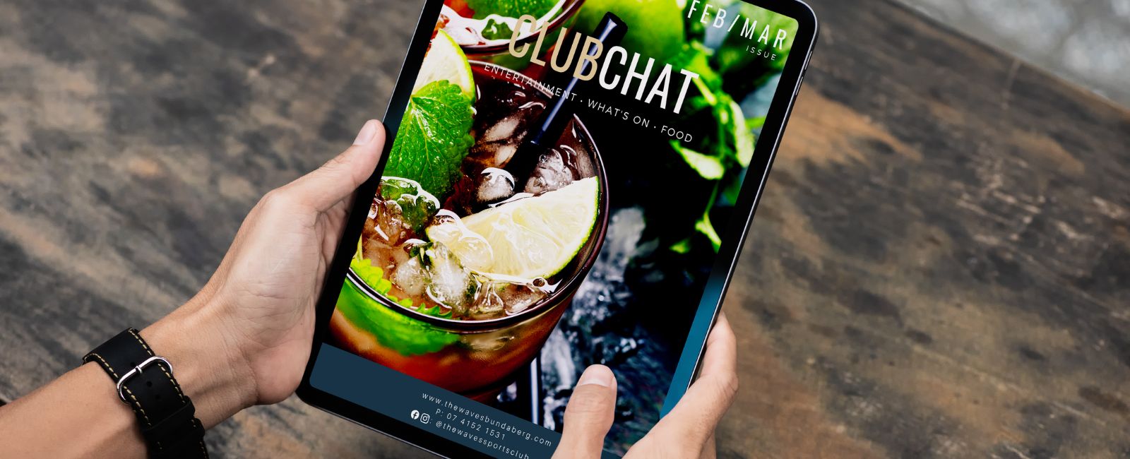 Hands holding tablet device with ClubChat magazine on screen